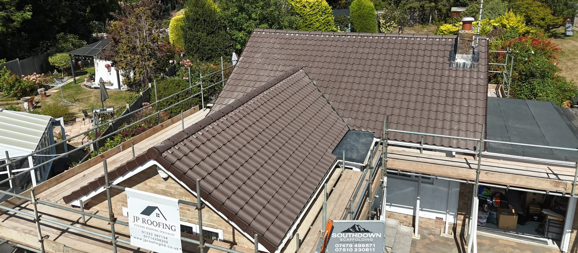 Tiled roofing project with scaffolding and a JP Roofing site board